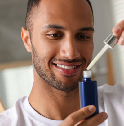Handsome man with cosmetic serum in hands indoors